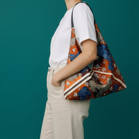 Modella indossa la borsa a triangolo anembags in tessuto stampato con dettagli in vera pelle su sfondo verde